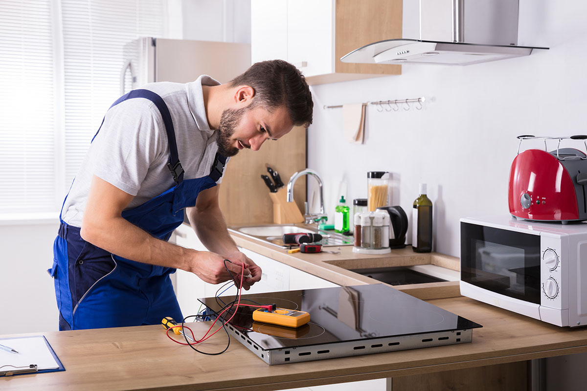 Técnico reparando placa de inducción en cocina